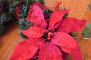 Outdoor holiday wreath- bell wired to center of poiinsettia